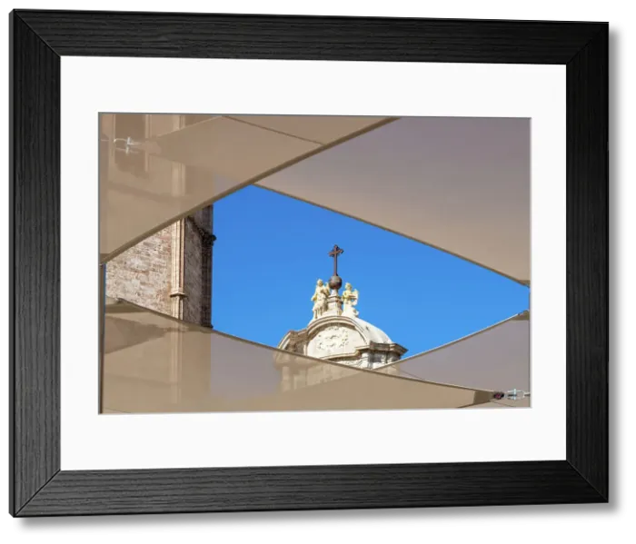 Framed Print : Stone angels and a cross on a bronze sphere on the top of the Iron Gate of La Catedral del Santo Caliz (Valencia Cathedral, or Cathedral of the Holy Chalice, or Saint Mary Cathedral), framed by the Plaza de la Reina canopies, Valencia, Spain Framed Print : Stone angels and a cross on a bronze sphere on the top of the Iron Gate of La Catedral del Santo Caliz (Valencia Cathedral, or Cathedral of the Holy Chalice, or Saint Mary Cathedral), framed by the Plaza de la Reina canopies, Valencia, Spain