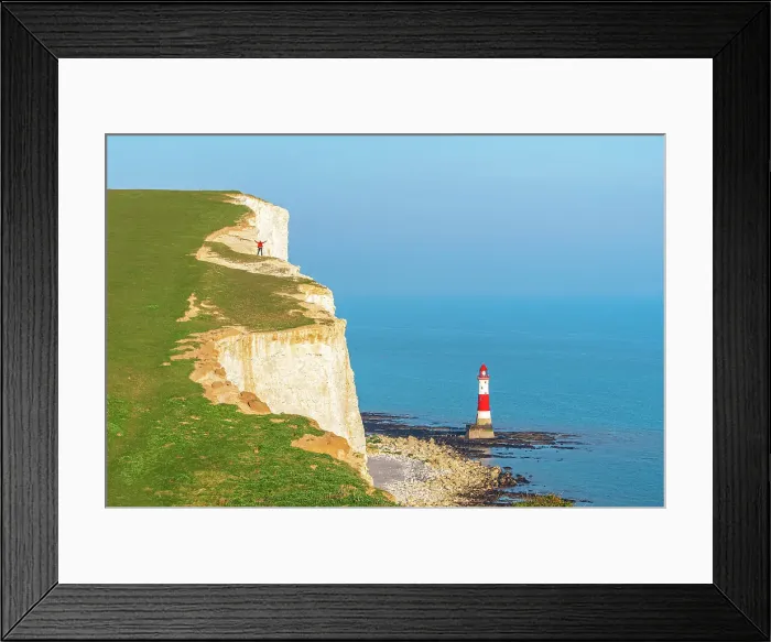 Framed Print : Hiker with arms raised stands on top of the white and chulky cliff overlooking Beachy Head lighthouse, Seven Sisters Country Park, South Downs National Park, Sussex, England, United Kingdom Framed Print : Hiker with arms raised stands on top of the white and chulky cliff overlooking Beachy Head lighthouse, Seven Sisters Country Park, South Downs National Park, Sussex, England, United Kingdom