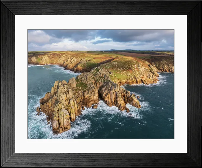 Framed Print : Aerial view of Treryn Dinas headland and Logan Rock near Porthcurno on the west coast of Cornwall, England. Winter (January) 2025