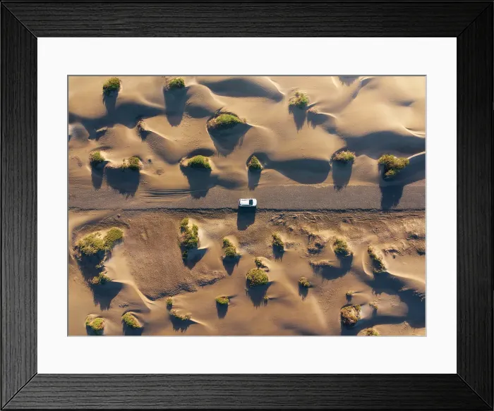 Framed Print : Aerial view of a car traveling through the sand dunes of Famara beach during sunrise, Caleta de Famara, Las Palmas, Lanzarote, Canary Islands, Spain Framed Print : Aerial view of a car traveling through the sand dunes of Famara beach during sunrise, Caleta de Famara, Las Palmas, Lanzarote, Canary Islands, Spain