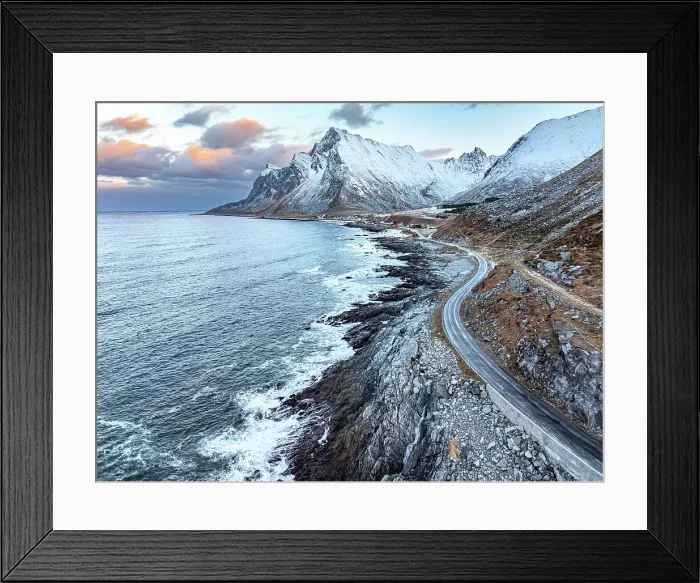 Framed Print : Empty winding road along the coastline with snowcapped mountains and Vikten village on background, Lofoten Islands, Norway Framed Print : Empty winding road along the coastline with snowcapped mountains and Vikten village on background, Lofoten Islands, Norway