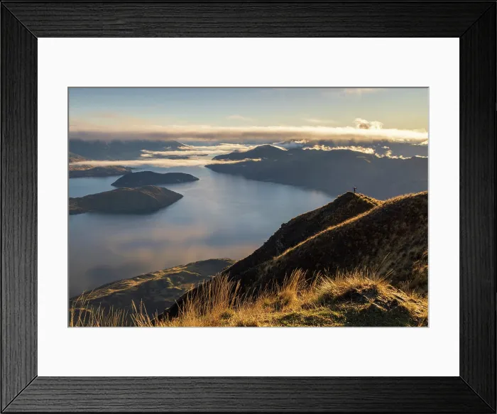 Framed Print : Woman standing on the summit of Coromandel Peak at dawn, overlooking Lake Wanaka, Otago, South Island, New Zealand. Autumn (May) 2025