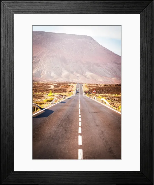 Framed Print : Cars driving on an asphalt road in the barren landscape towards volcanic mountains, Corralejo, Fuerteventura, Canary Islands, Spain Framed Print : Cars driving on an asphalt road in the barren landscape towards volcanic mountains, Corralejo, Fuerteventura, Canary Islands, Spain