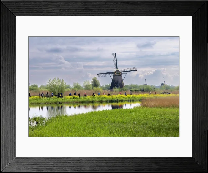 Framed Print : A group of cyclists pass by a windmill at Kinderdijk, South Holland, Netherlands Framed Print : A group of cyclists pass by a windmill at Kinderdijk, South Holland, Netherlands