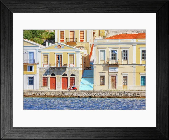 Framed Print : Vespa driving along Gialos Harbour quay, Gialos, Symi Island, Dodecanese Islands, Greece Framed Print : Vespa driving along Gialos Harbour quay, Gialos, Symi Island, Dodecanese Islands, Greece
