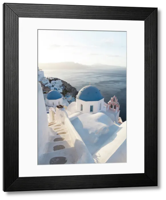 Framed Print : Blue domed churches, white-washed houses and steps with caldera view in the distance, Oia, Santorini, Cyclades Islands, Greece Framed Print : Blue domed churches, white-washed houses and steps with caldera view in the distance, Oia, Santorini, Cyclades Islands, Greece