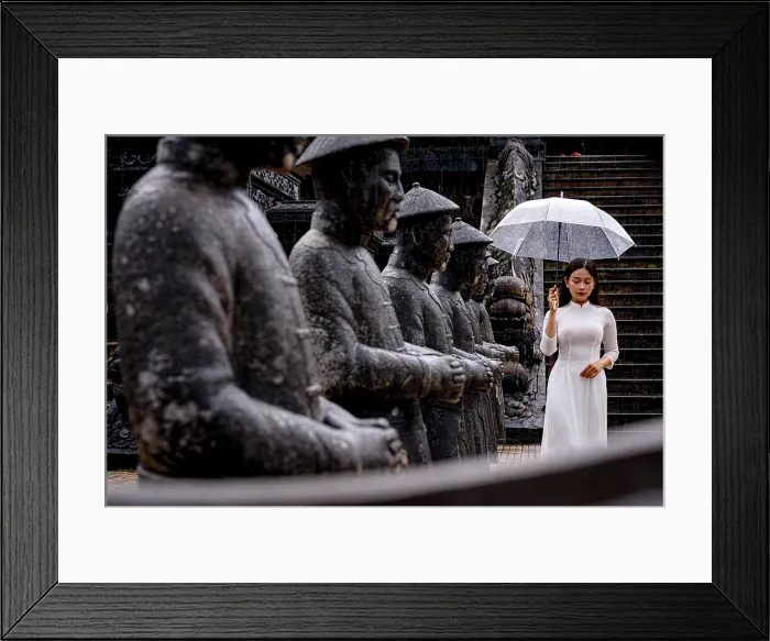 Framed Print : Woman in white ao dai by statues with umbrella, Khai Dinh Mausoleum, Hue, Vietnam. (MR)