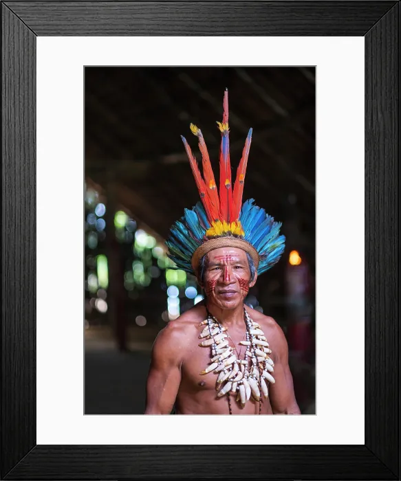 Framed Print : South America, Brazil, Amazonas, Rio Negro. Amazonian indigenous Tatuyo cacique (chief) wearing macaw feather headdress crown and standing inside a maloca (long house)