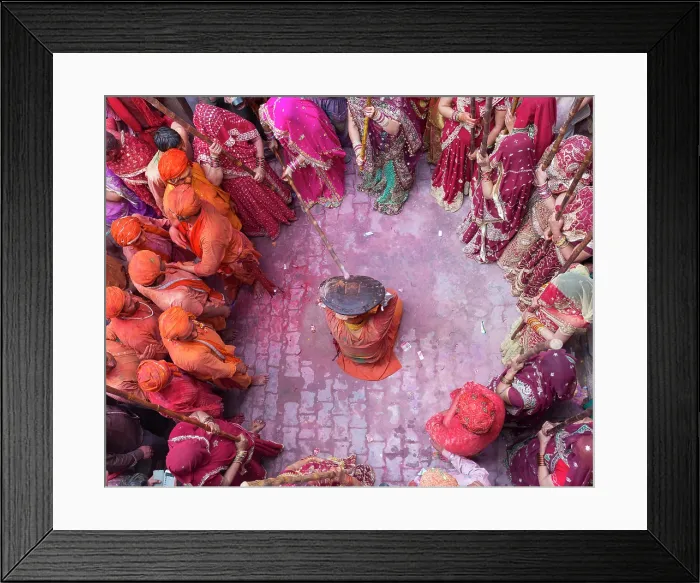 Framed Print : India, Uttar Pradesh, Mathura, Barsana, A man protects himself with a shield from women with sticks during the Lathmar Holi Festival Framed Print : India, Uttar Pradesh, Mathura, Barsana, A man protects himself with a shield from women with sticks during the Lathmar Holi Festival