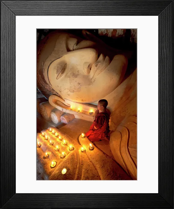 Framed Print : Myanmar, Burma, Mandalay, Bagan, Pagan, A novice Buddhist monk praying at the foot of a reclining Buddha with candles Framed Print : Myanmar, Burma, Mandalay, Bagan, Pagan, A novice Buddhist monk praying at the foot of a reclining Buddha with candles