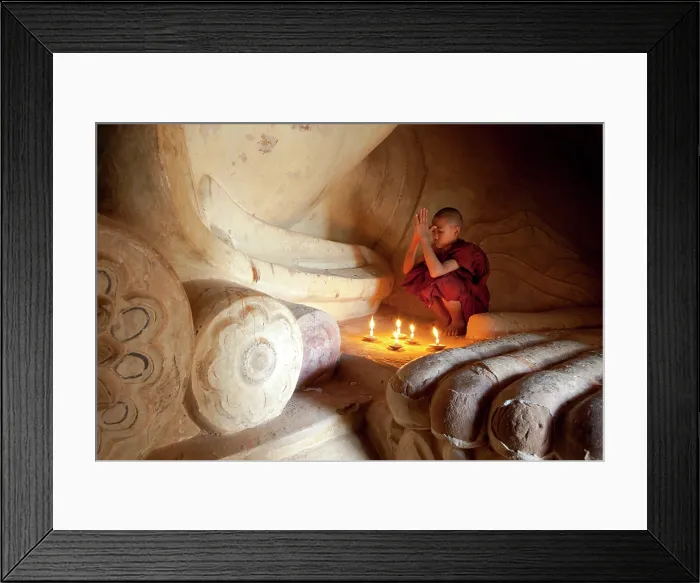 Framed Print : Myanmar, Burma, Mandalay, Bagan, Pagan, A novice Buddhist monk praying at the foot of a reclining Buddha with candles Framed Print : Myanmar, Burma, Mandalay, Bagan, Pagan, A novice Buddhist monk praying at the foot of a reclining Buddha with candles
