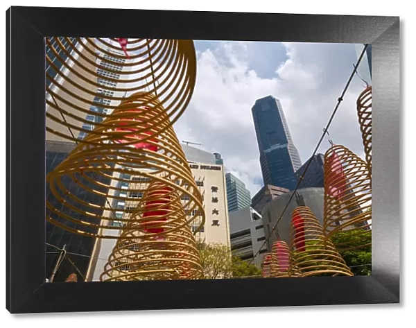 Singapore, Singapore, Raffles Place. Spiral incense coils with city skyline in background at Wak Hai Cheng