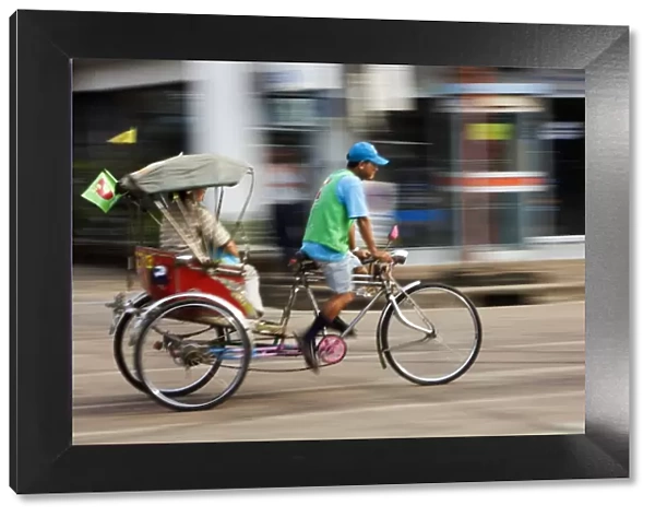 Thailand, Sakhon Nakhon, Sakhon Nakhon. A saamlaw (three wheeled pedicab) driver peddles his passengers through the streets of