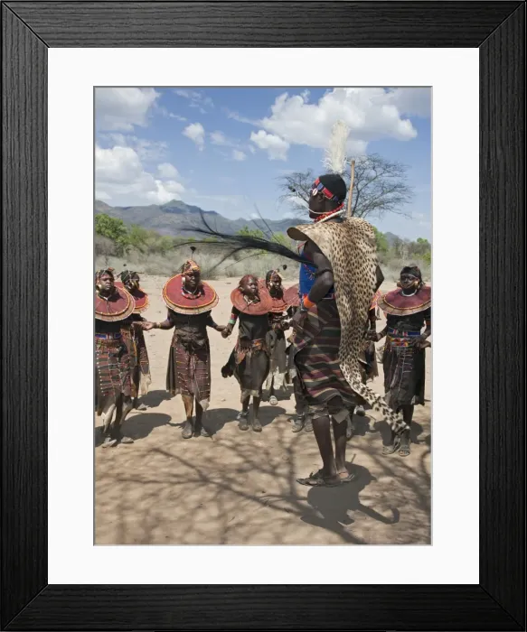 Framed Print : A Pokot warrior wearing a cheetah skin jumps high in the air surrounded by young women to celebrate an Atelo ceremony. The Pokot are pastoralists speaking a Southern