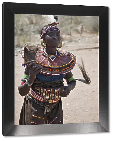 An old Pokot woman dancing during an Atelo ceremony. The cow horn container usually contains animal fat