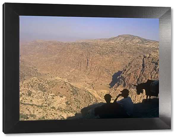 Jordan, Dana Biosphere Reserve. Dana village youths gaze over the spectacular lip of Wadi Dana towards