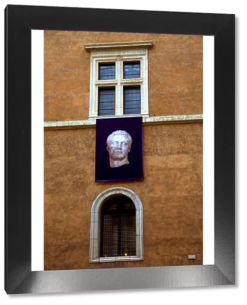 Rome, Italy; A Roman statue advertised on the walls of Palazzo Venezia