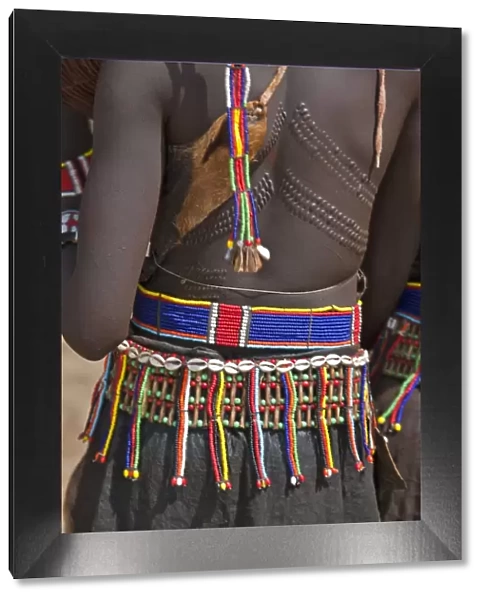 A Pokot woman in traditional attire with patterned cicatrices on her back attends an Atelo ceremony