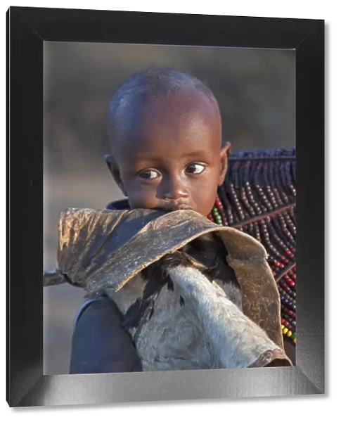 A Pokot child wrapped in a goatskin in his mothers arms. The Pokot are pastoralists speaking a Southern Nilotic language
