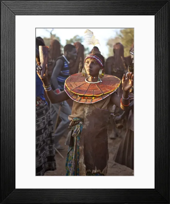 Framed Print : During a Ngetunogh ceremony, the mother of a Pokot initiate sings and dances holding high the cowhorn container she used to smear fat over the masks of her son and other boys as Framed Print : During a Ngetunogh ceremony, the mother of a Pokot initiate sings and dances holding high the cowhorn container she used to smear fat over the masks of her son and other boys as