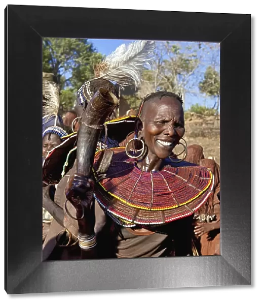 During a Ngetunogh ceremony, the mother of a Pokot initiate sings and dances holding high the cowhorn container she used to smear fat over the masks of her son and other boys as