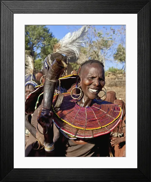 Framed Print : During a Ngetunogh ceremony, the mother of a Pokot initiate sings and dances holding high the cowhorn container she used to smear fat over the masks of her son and other boys as