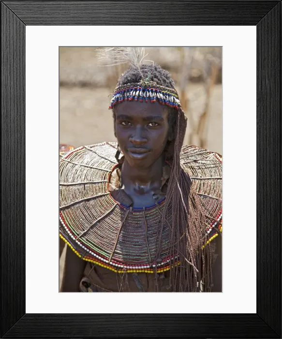 Framed Print : Towards the conclusion of a Ngetunogh ceremony, an initiate must put on his mothers jewellery for a day before removing the wild sisal face mask he has worn for 2-3 months Framed Print : Towards the conclusion of a Ngetunogh ceremony, an initiate must put on his mothers jewellery for a day before removing the wild sisal face mask he has worn for 2-3 months