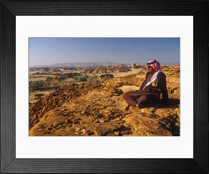 Framed Print : Saudi Arabia, Madinah, nr. Al-Ula, Madain Saleh (aka Hegra). A Saudi man gazes at stark cliffs Framed Print : Saudi Arabia, Madinah, nr. Al-Ula, Madain Saleh (aka Hegra). A Saudi man gazes at stark cliffs