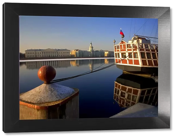 Russia, St. Petersburg; A wooden ship at pier on the partly frozen Neva River with the Kunstkamera in