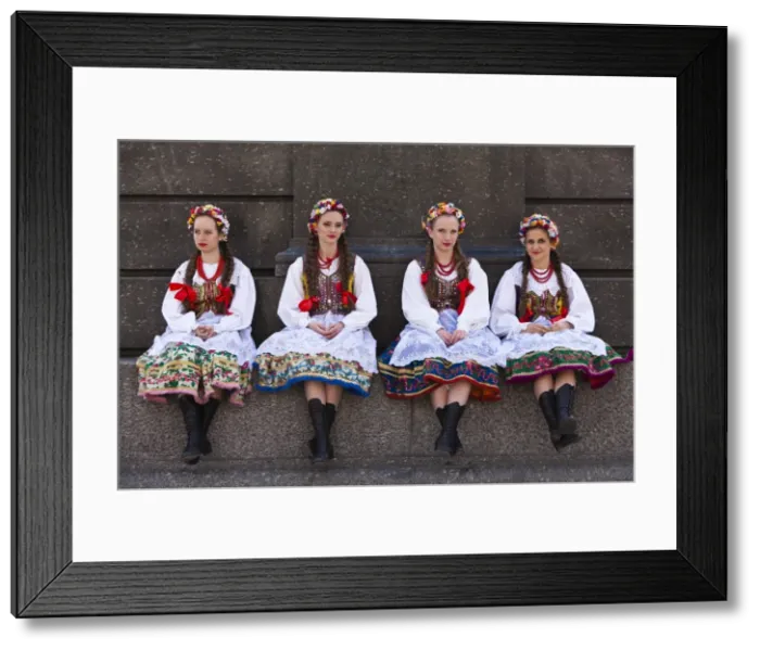 Framed Print : Poland, Cracow. Polish girls in traditional dress sitting at the base of the statue of Adam Mickiewicz, preparing to dance in Framed Print : Poland, Cracow. Polish girls in traditional dress sitting at the base of the statue of Adam Mickiewicz, preparing to dance in