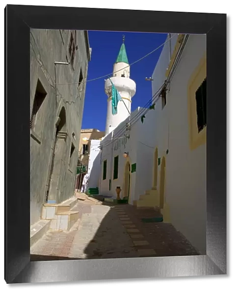 Tripoli, Libya; A minaret and the Libyan flag visible on one of the Mosques in the Ancient Medina of