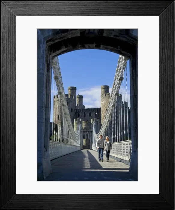 Framed Print : UK, North Wales; Conwy. Couple on the elegant Suspension Bridge built by Thomas Telford across the Conwy River to the imposing Framed Print : UK, North Wales; Conwy. Couple on the elegant Suspension Bridge built by Thomas Telford across the Conwy River to the imposing