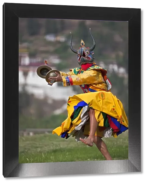 A masked dancer with cymbals performs Drametse Nga Cham (the religious masked dance)
