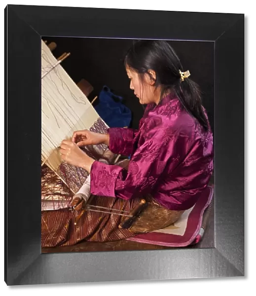 A woman weaves an intricate pattern in silk on her traditional wooden loom. The broad leather belt around her buttocks is the reason for naming this particular type of loom backstrap loom