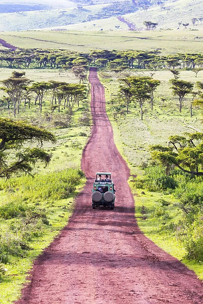 A 4-wheel drive safari vehicle drives along a red track near the Ngorongoro Crater