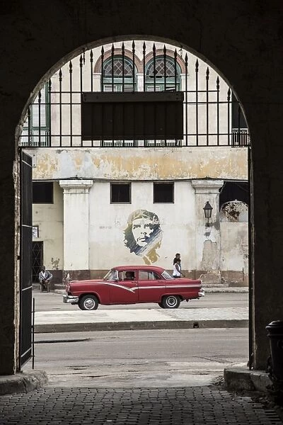 50s Classic American car passing a mural of Che Guevara, Habana Vieja, Havana, Cuba