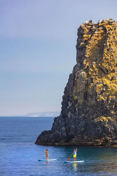 Aci Trezza, Sicily. People riding kayak with a sea stack in the background