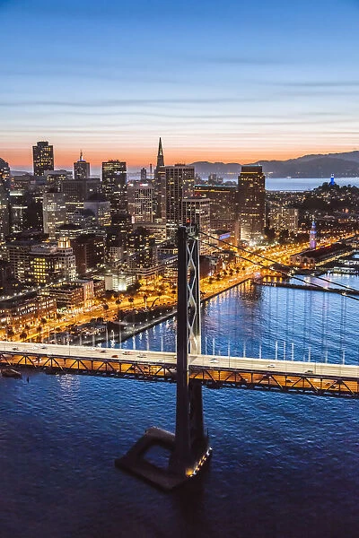 Aerial of downtown district at dusk with Bay bridge in the foreground, San Francisco