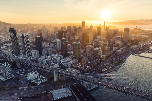 Aerial of downtown district at sunset with Bay bridge in the foreground, San Francisco