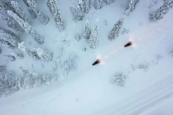 Aerial of snowmobiles on road through snow-covered forest, Kuusamo, Finland