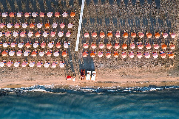 Aerial view of beach umbrellas in a row on sand beach washed by waves, Vieste