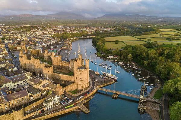 Aerial view of Caernarfon Castle and town in gorgeous evening sunlight, Caernarfon, Wales, UK. Spring (May) 2023