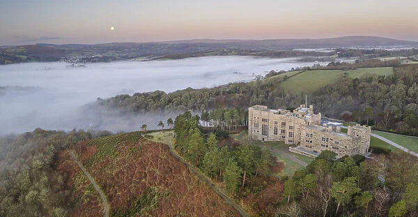 Aerial view of Castle Drogo at dawn on a misty winter morning, Dartmoor National Park, Devon, England. Winter (March) 2022