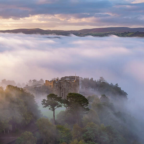 Aerial view of Castle Drogo emerging from a sea of morning mist, Dartmoor National Park, Devon, England. Autumn (October) 2023