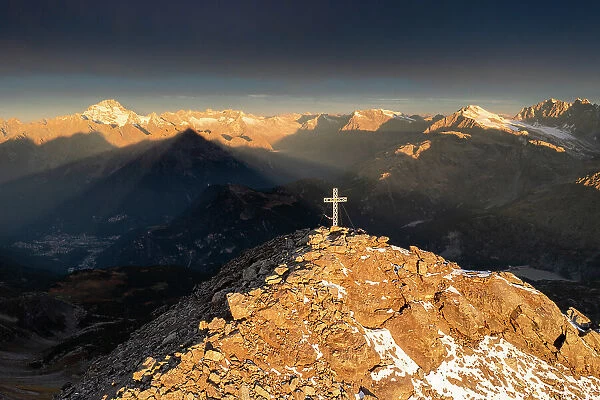 Aerial view of the crucifix on the top of Pizzo Scalino with view on the Mount Disgrazia at sunrise. Valmalenco, Valtellina, Lombardy, Italy