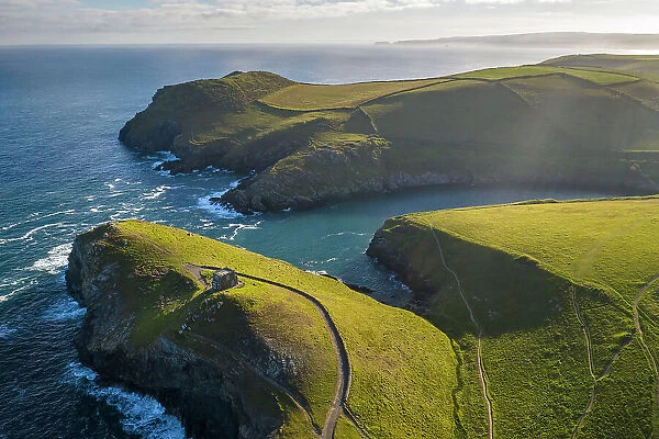 Aerial view of Doyden Castle and Port Quin surrounded by rugged Cornish coastline, Cornwall, England. Spring (June) 2022