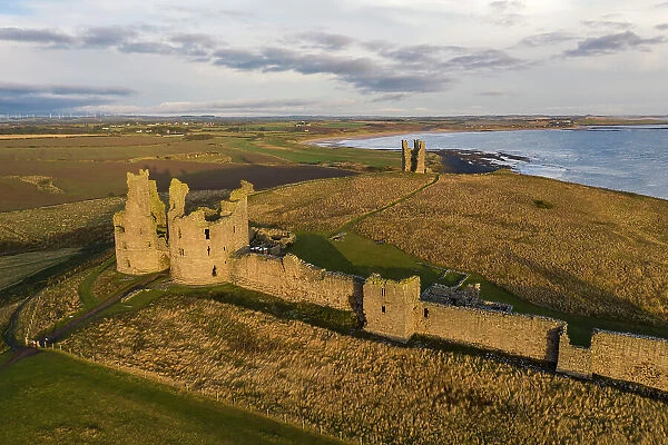 Aerial view of Dunstanburgh Castle on the Northumbrian coast, Embleton, Northumberland, England. Autumn (October) 2021