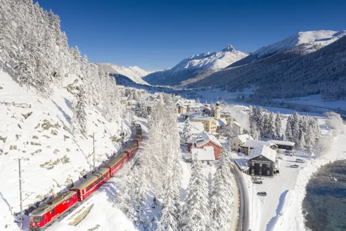 Framed Print : Aerial view of famous red Bernina Express train crossing the snowy village of Madulain Framed Print : Aerial view of famous red Bernina Express train crossing the snowy village of Madulain