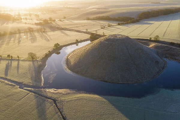 Aerial view of a flooded Silbury Hill on a frosty winter morning, Avebury, Wiltshire, England. Winter (February) 2023