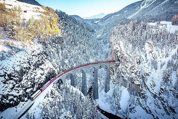 Aerial view of the Swiss red train crossing Landwasser viaduct in the cold winter, Filisur, Graubunden canton, Switzerland